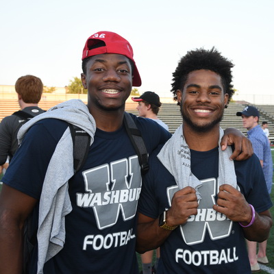Two guys smile while at a Washburn football game.